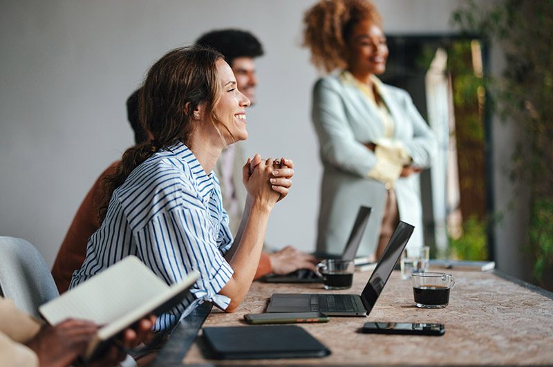 Gruppe von Studenten/-innen Eine Gruppe junger Studenten hört gespannt einem Vortrag zu, während ihre Laptops vor ihnen auf den Tischen stehen.